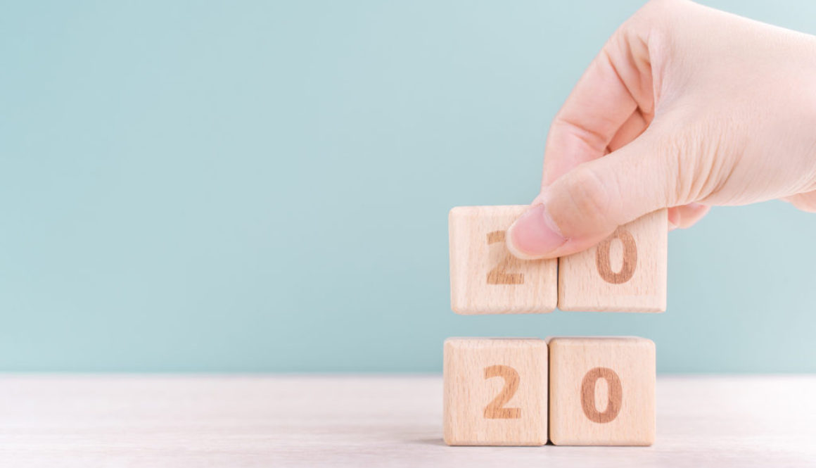 Abstract 2020 & 2019 New year countdown design concept - woman holding wood blocks cubes on wooden table and green background, close up, copy space.